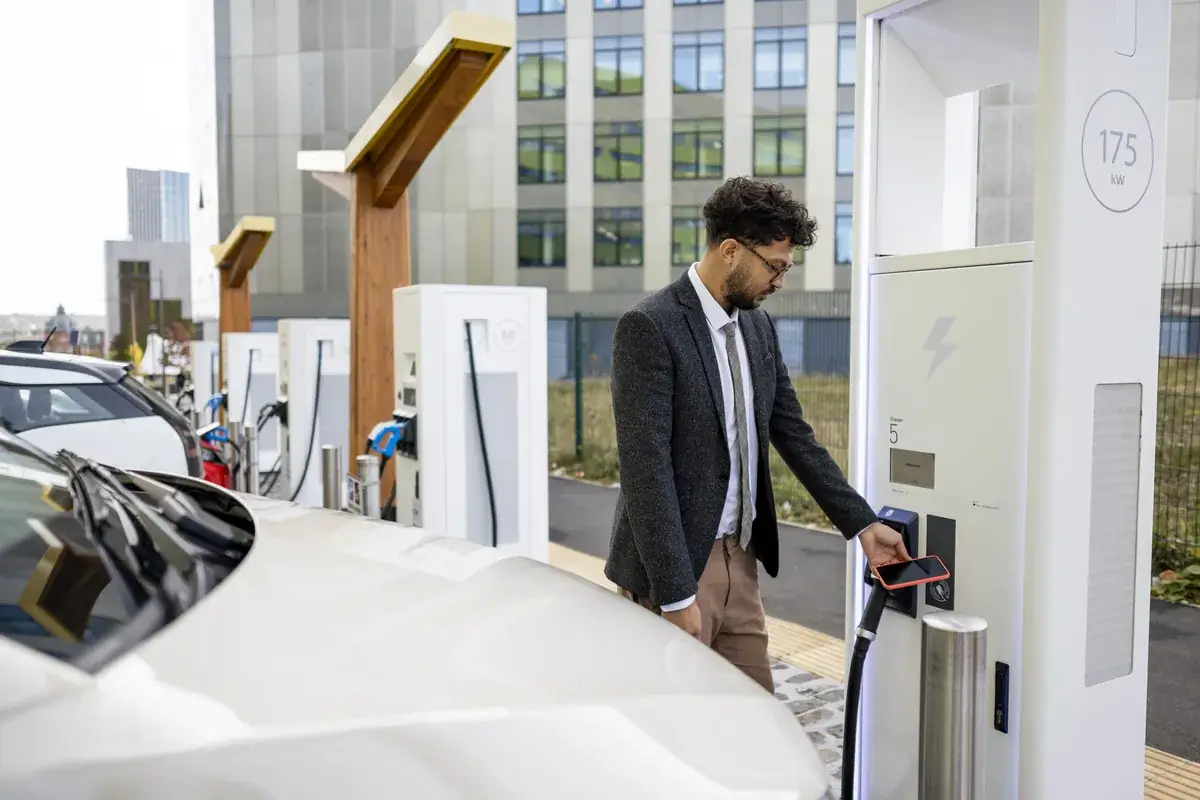Profesional cargando un coche eléctrico en un punto de recarga de empresa
