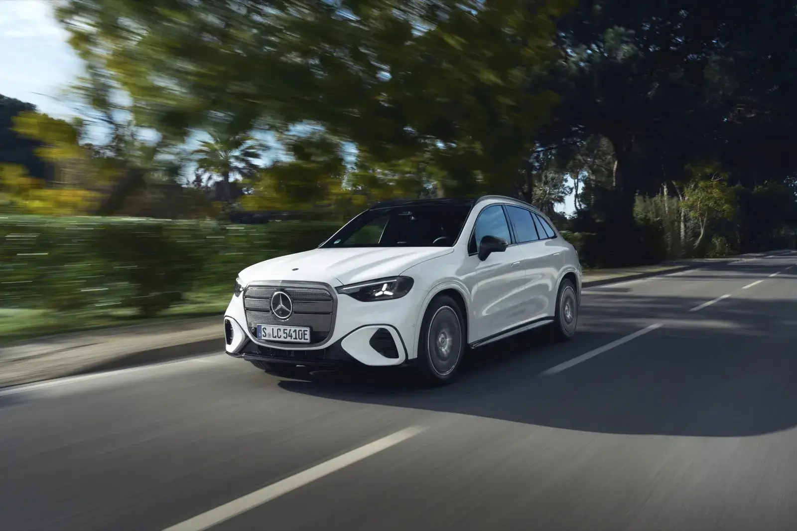 Mercedes GLC 300 e blanco circulando por una carretera arbolada