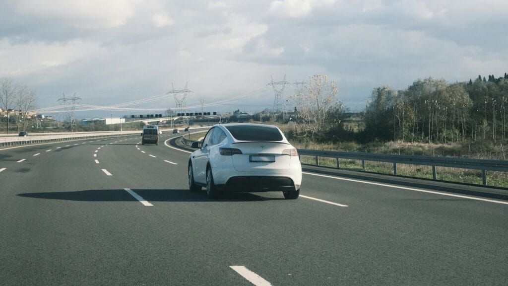 Coche eléctrico circulando por autovía bajo un cielo nublado