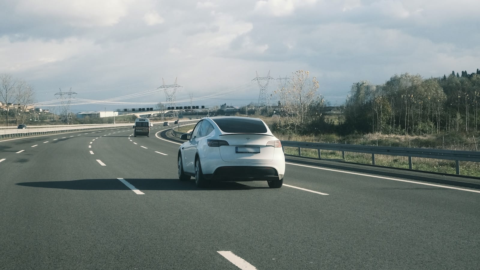 Coche eléctrico circulando por autovía bajo un cielo nublado